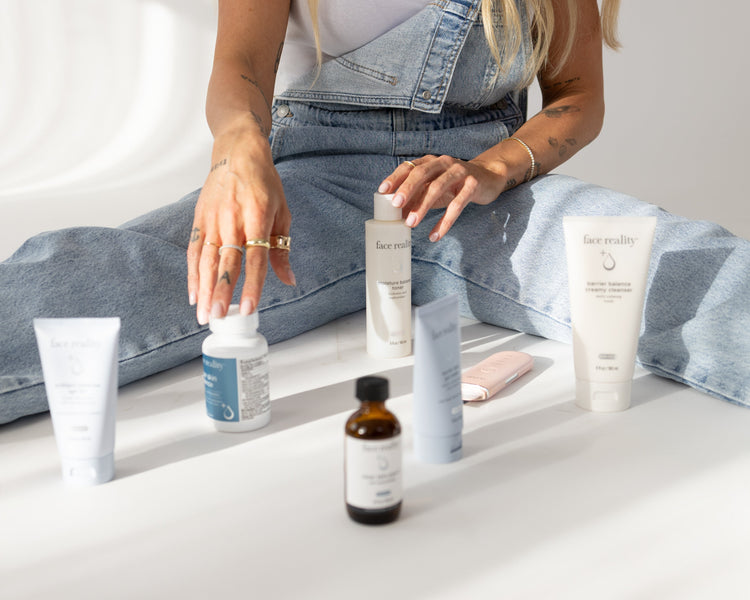 Woman sitting on a white surface with skincare products around her